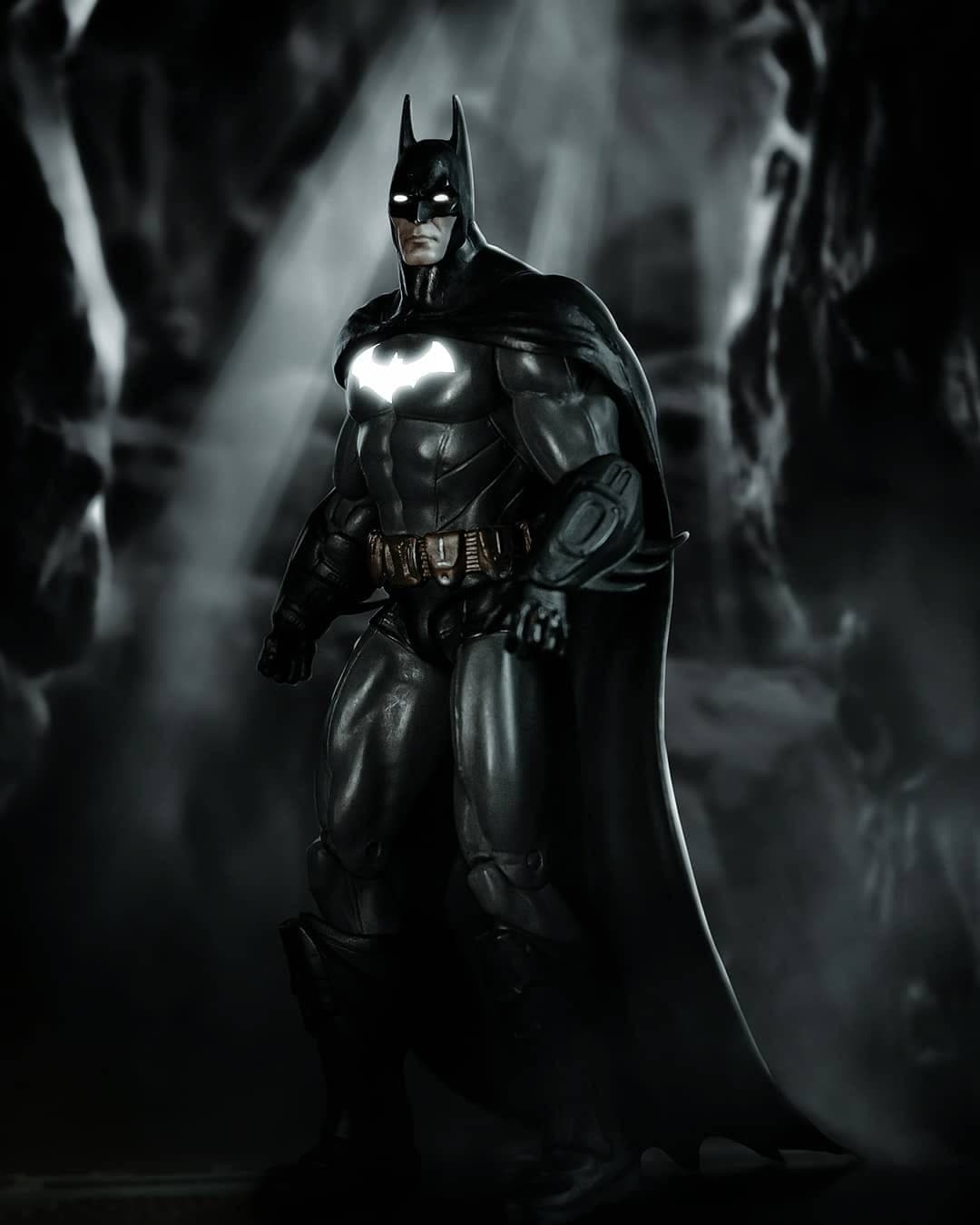 Batman figure lit through drifting haze in a dark cave